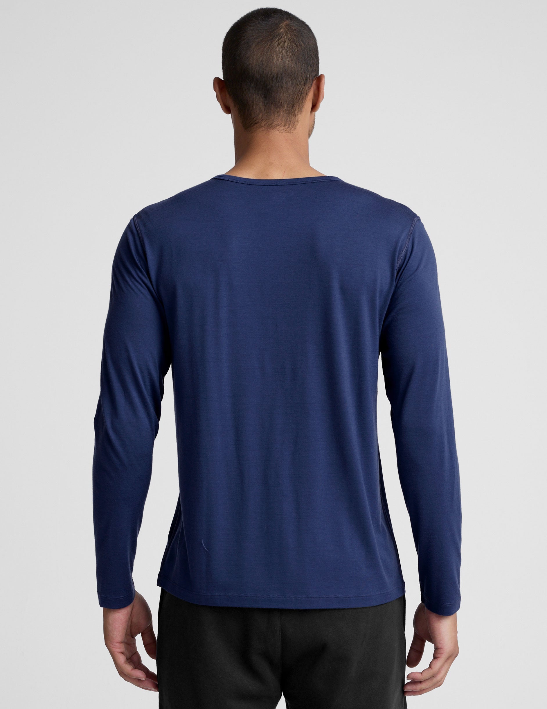 man wearing a blue long-sleeve shirt against a plain background.