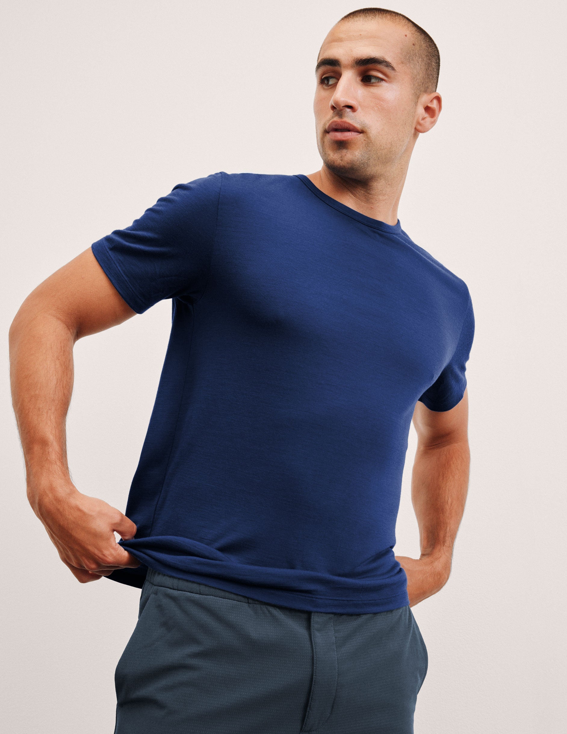 man wearing a blue crew neck t-shirt against a plain background.