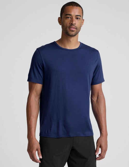 man wearing a blue crew neck t-shirt against a plain background.