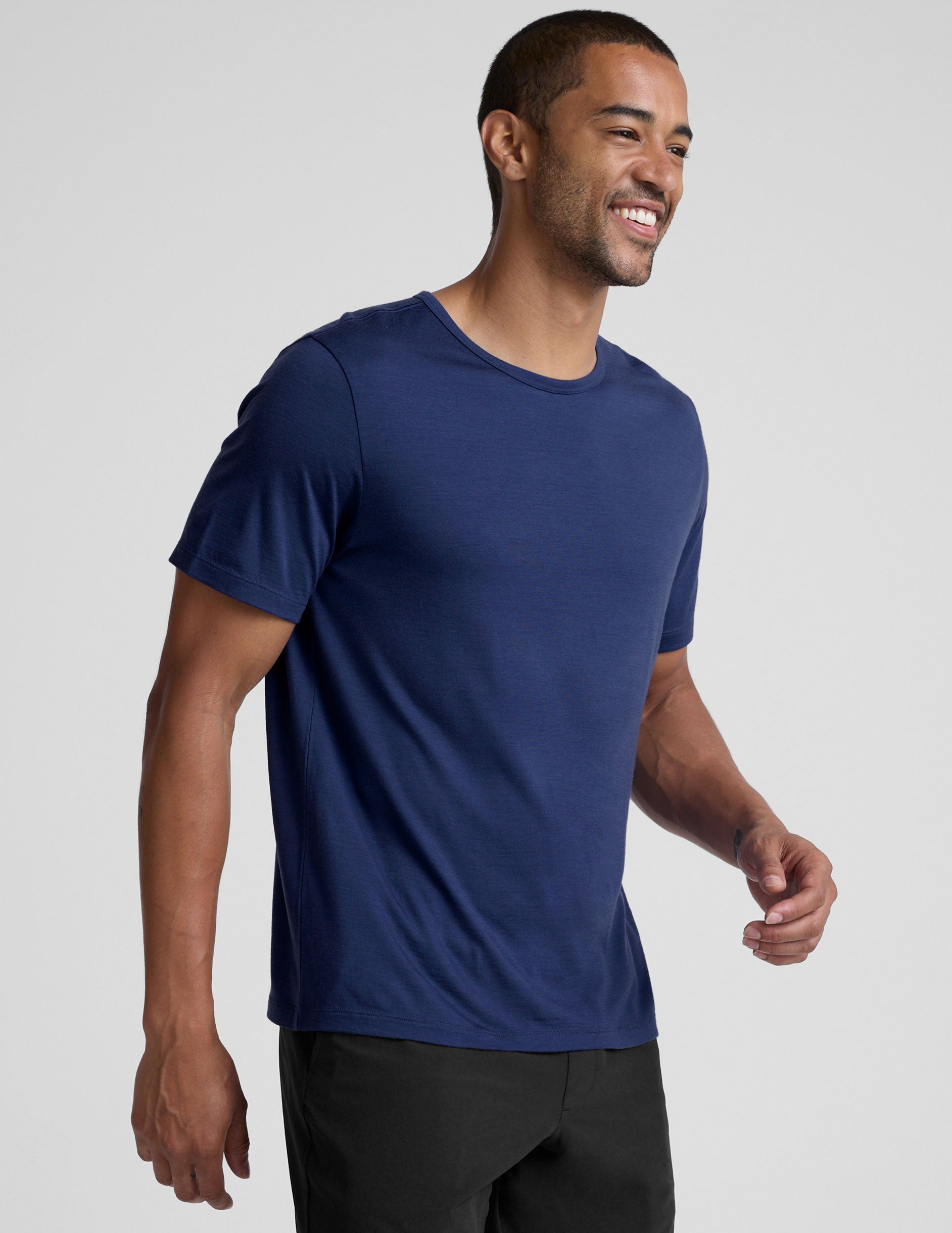 man wearing a blue crew neck t-shirt against a plain background.