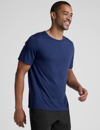 man wearing a blue crew neck t-shirt against a plain background.
