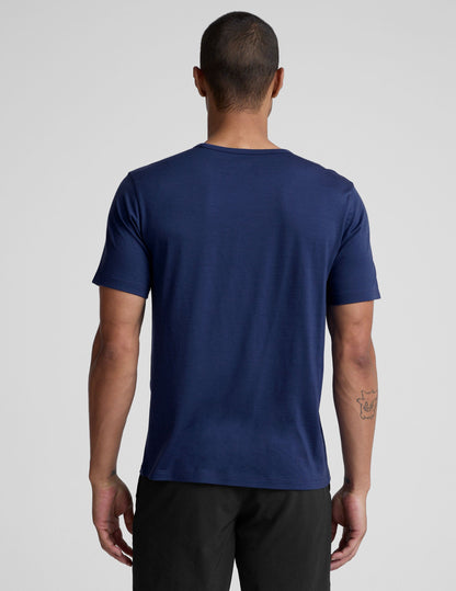 man wearing a blue crew neck t-shirt against a plain background.