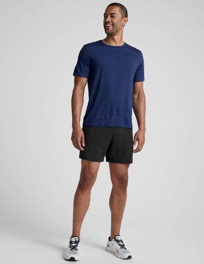 man wearing a blue crew neck t-shirt against a plain background.