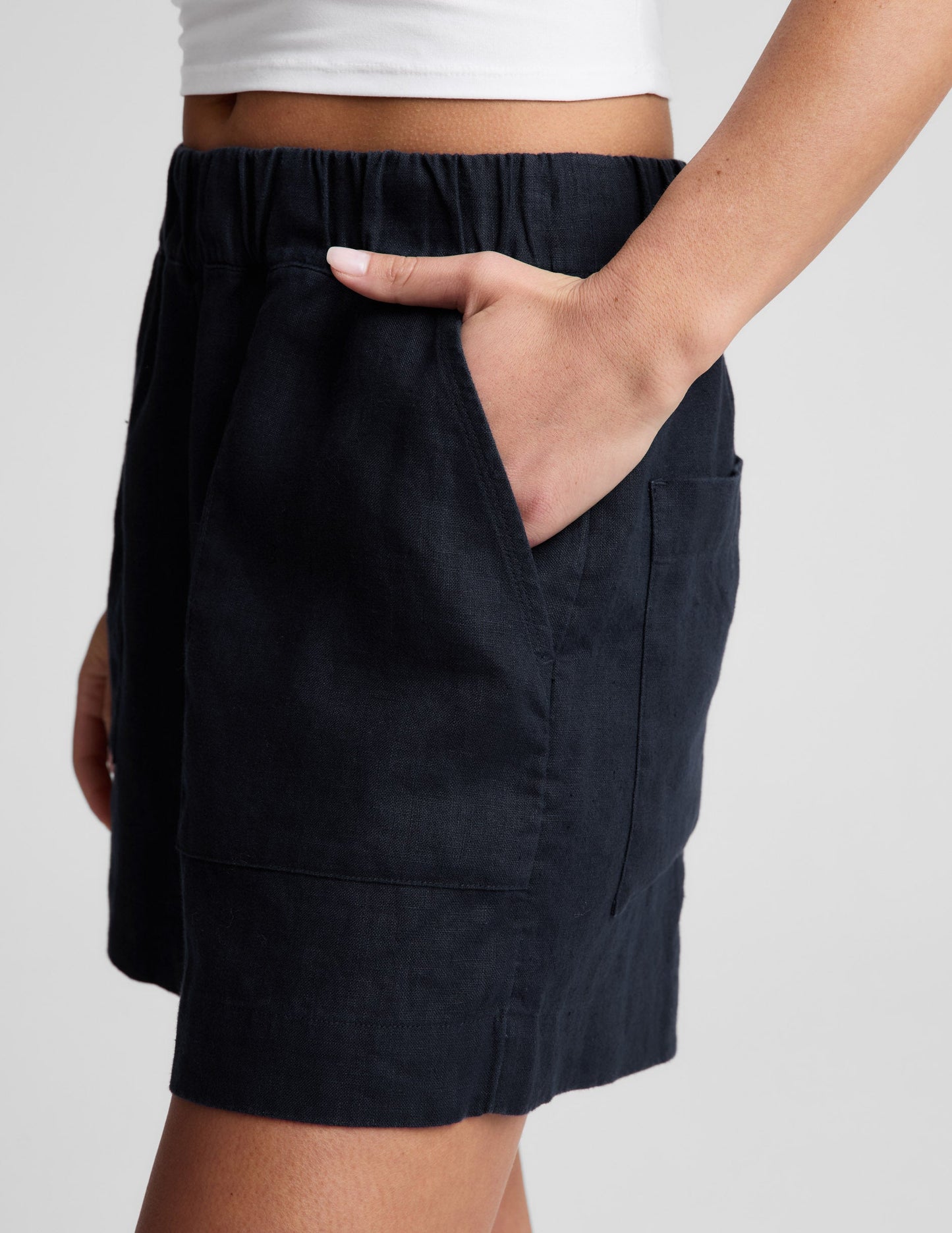 Side view of black SoftWash Linen Easy Short with an elastic waistband and front pockets on a model.