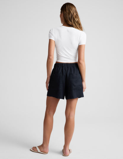 Rear view of a woman wearing black SoftWash Linen Easy Short with elastic waistband and back patch pockets.