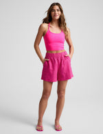 Fuchsia SoftWash Linen Easy Short on a model with hands in pockets, featuring a mid-rise elastic waist and patch pockets.