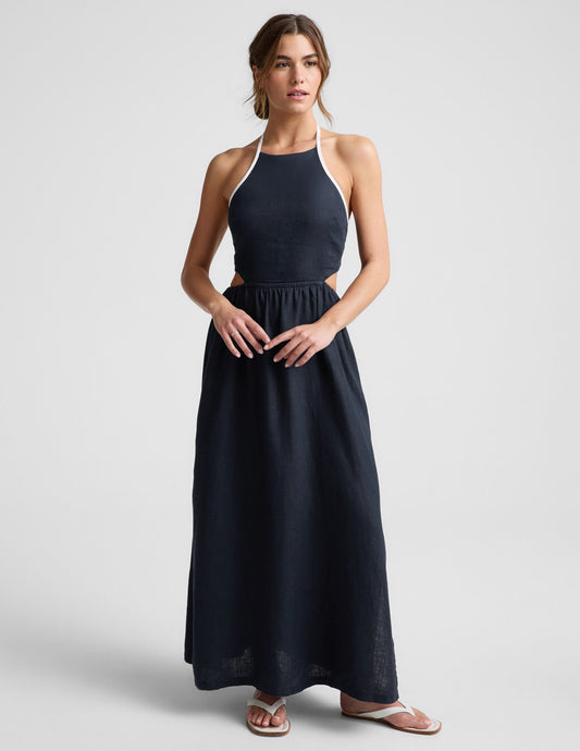 Woman wearing a navy blue halter neck midi dress on a light gray background.