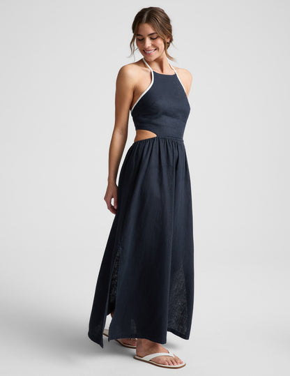 Woman wearing a navy blue halter neck midi dress on a light gray background.