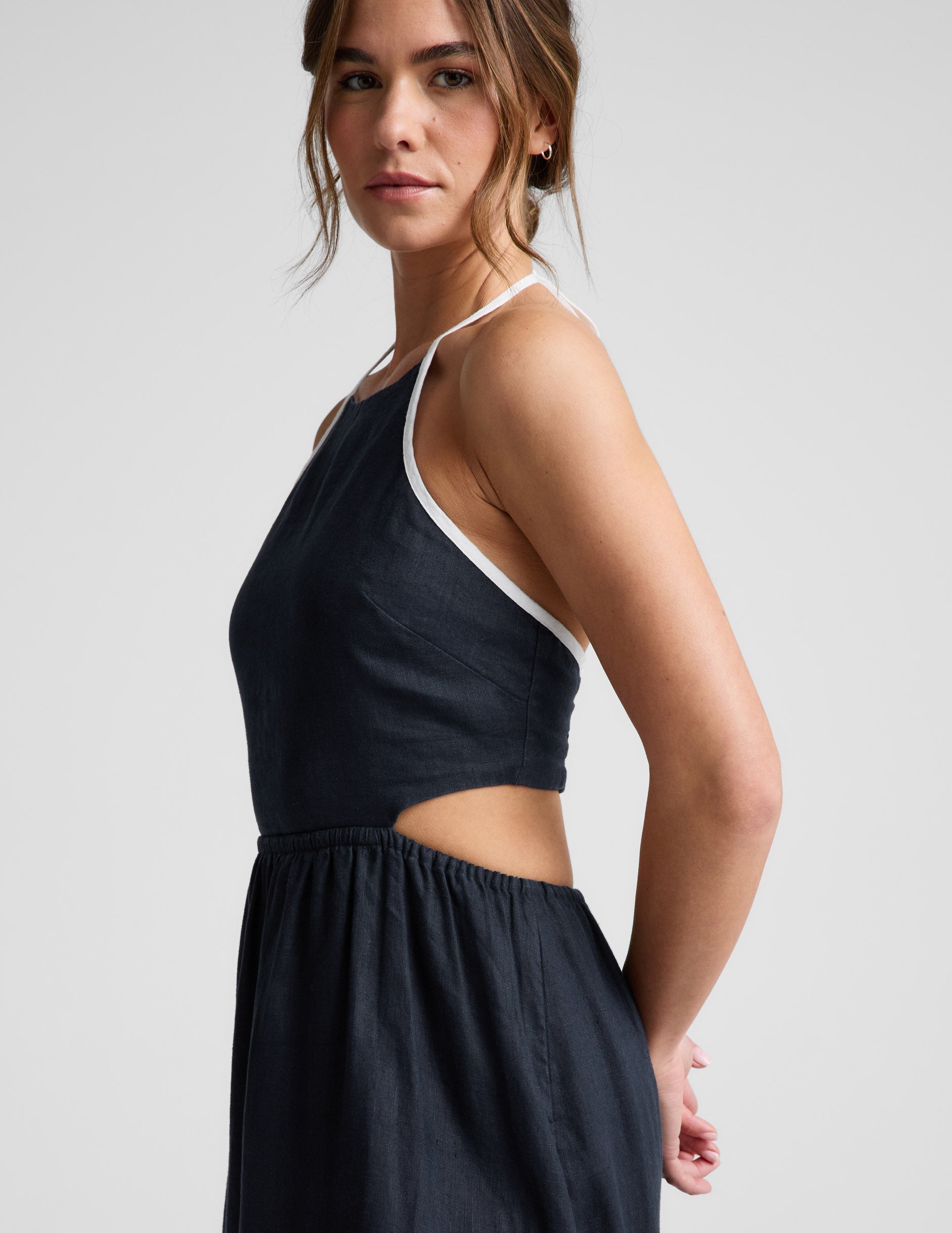 Woman wearing a navy blue halter neck midi dress on a light gray background.