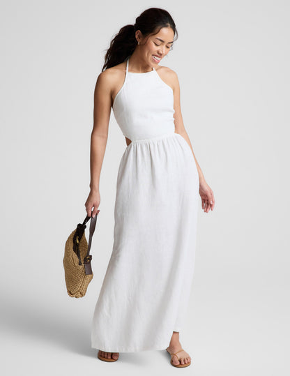 Woman wearing a white midi length halter dress against a plain background.