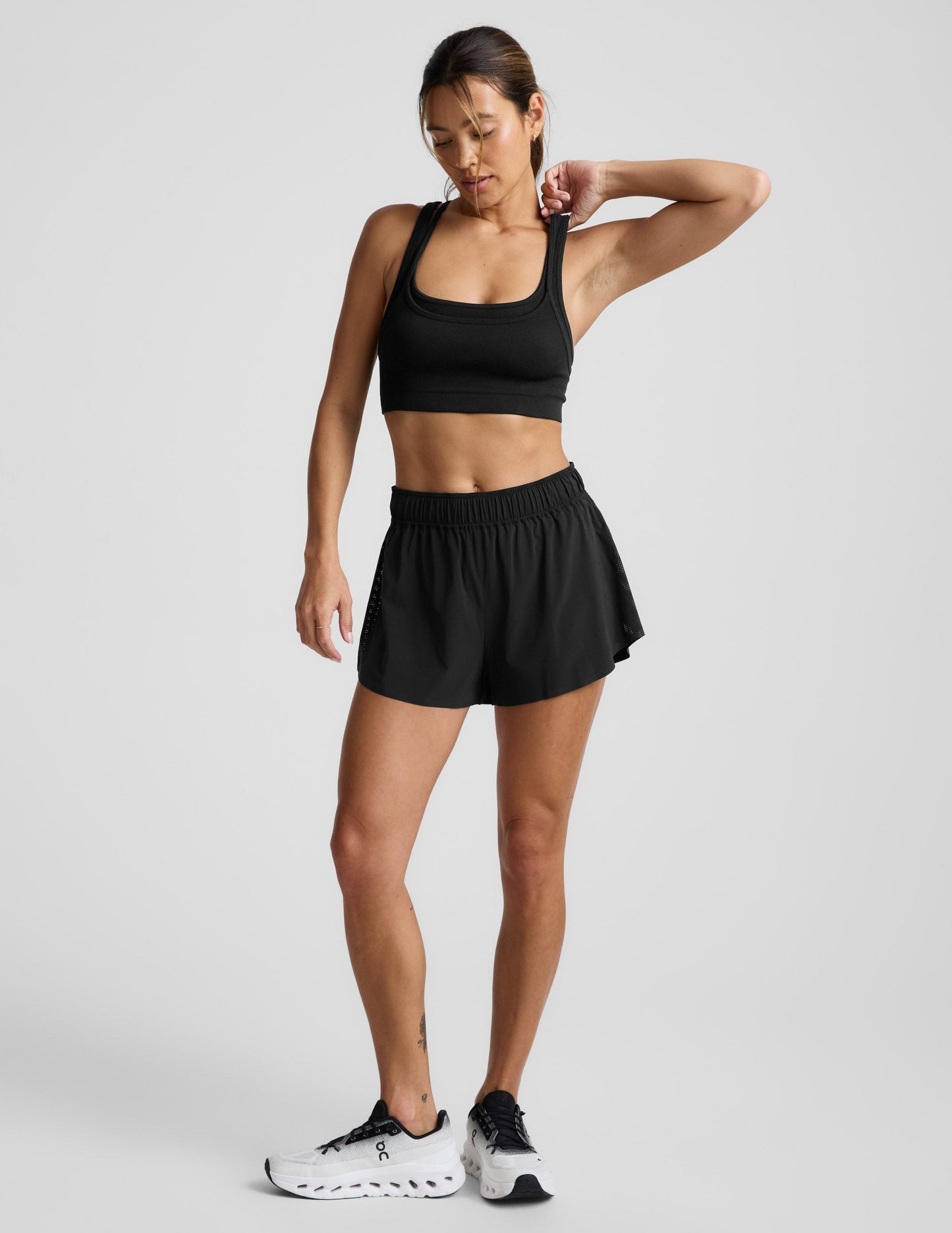 Woman wearing a black sports bra and shorts against a plain background.