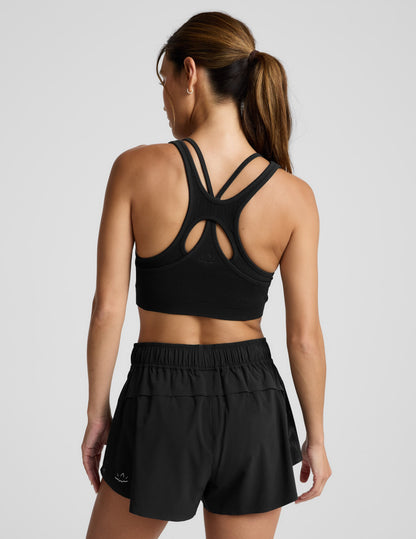 Woman wearing a black sports bra and shorts against a plain background.
