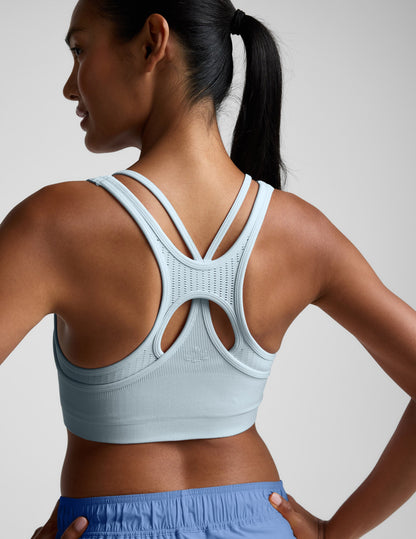 Woman wearing a light blue sports bra and shorts on a plain background.