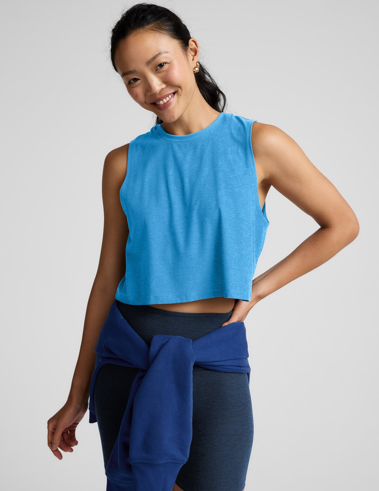 Woman wearing a light blue sleeveless top and biker shorts against a plain background.