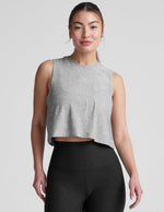 Woman wearing a gray cropped sleeveless top and black leggings on a plain background.