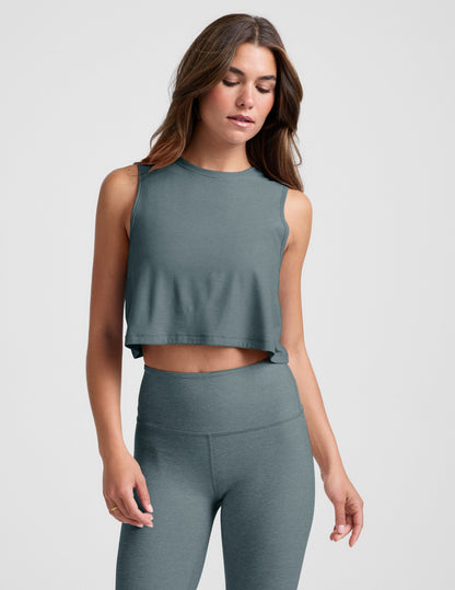 Woman wearing a gray sleeveless top and leggings on a light gray background.