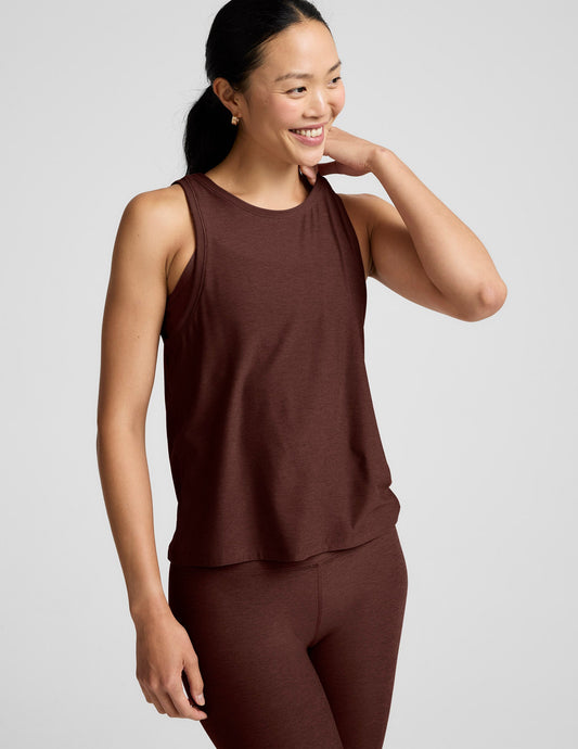 Woman wearing a brown tank top and brown high-waisted leggings against a plain background.