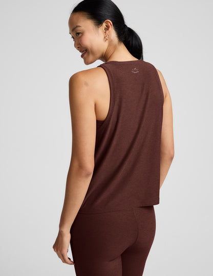 Woman wearing a brown tank top and brown high-waisted leggings against a plain background.