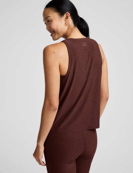 Woman wearing a brown tank top and brown high-waisted leggings against a plain background.