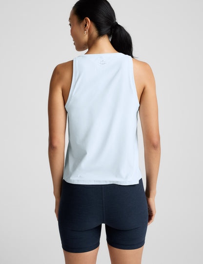 Woman wearing a light blue sleeveless top and navy blue biker shorts on a light gray background.