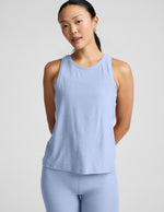 Woman wearing a light blue sleeveless top and leggings against a plain background.