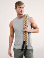 Man wearing a gray tank top and green shorts against a plain background.