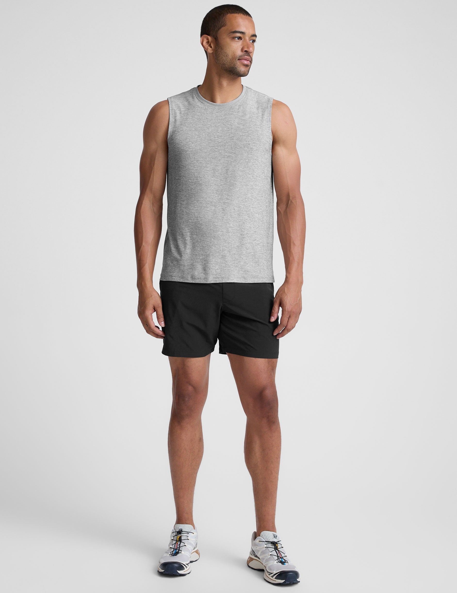 man wearing a gray sleeveless shirt against a plain background.