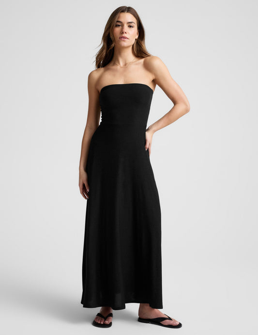 Woman wearing a black strapless maxi dress against a light gray background.