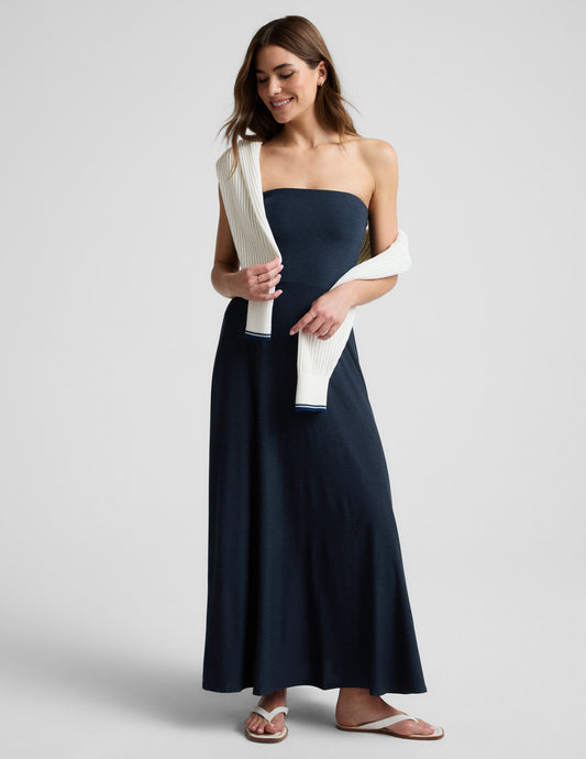 Woman wearing a strapless navy blue maxi dress on a light gray background.