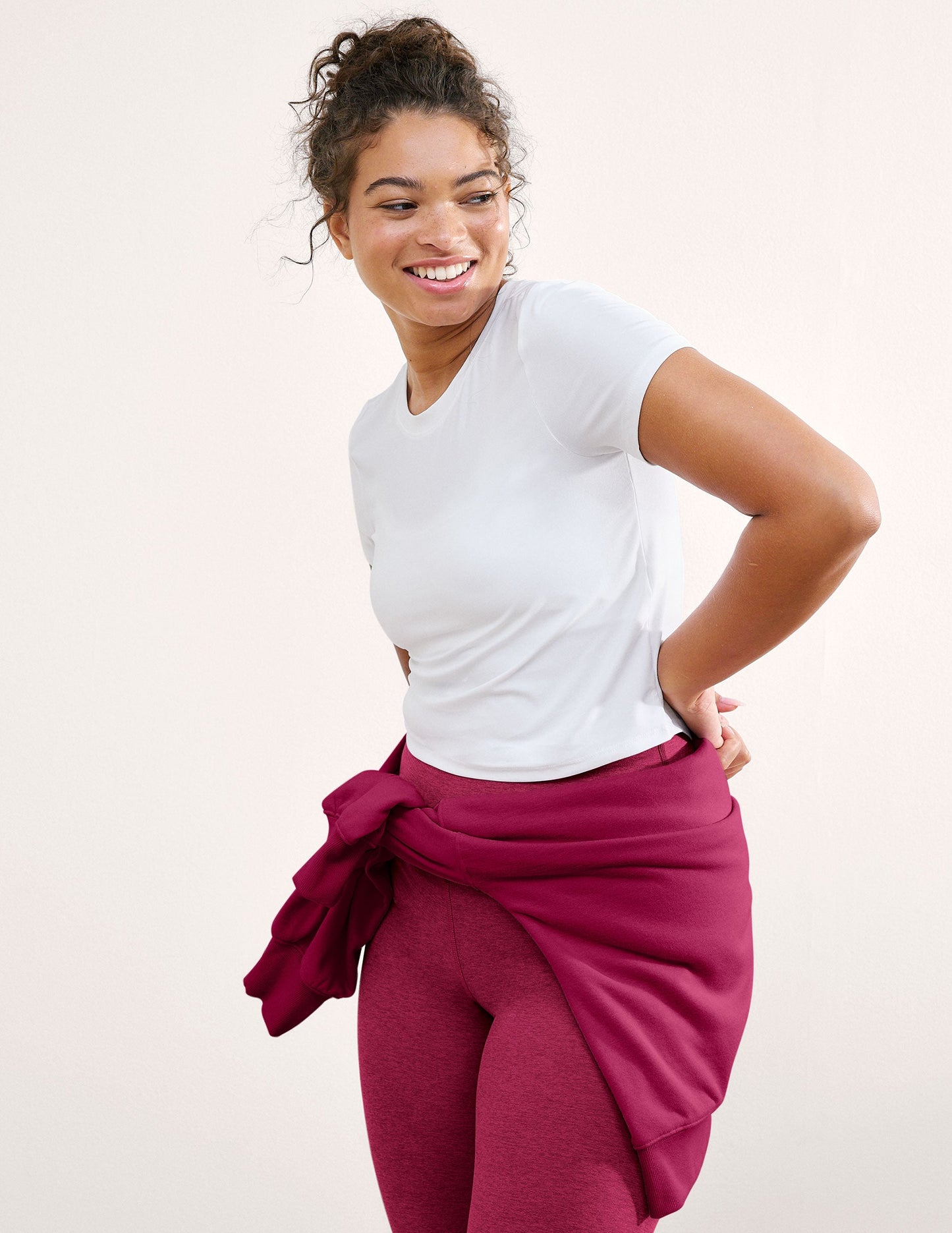 Woman wearing a white t-shirt and magenta leggings on a plain background.