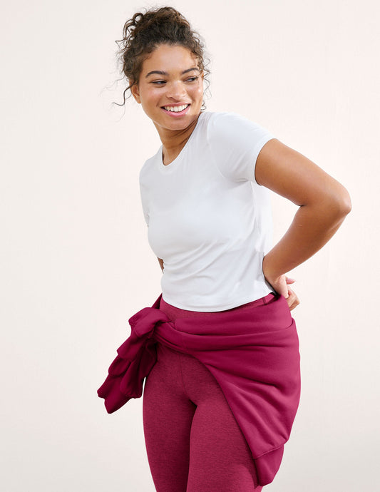 Woman wearing a white t-shirt and magenta leggings on a plain background.