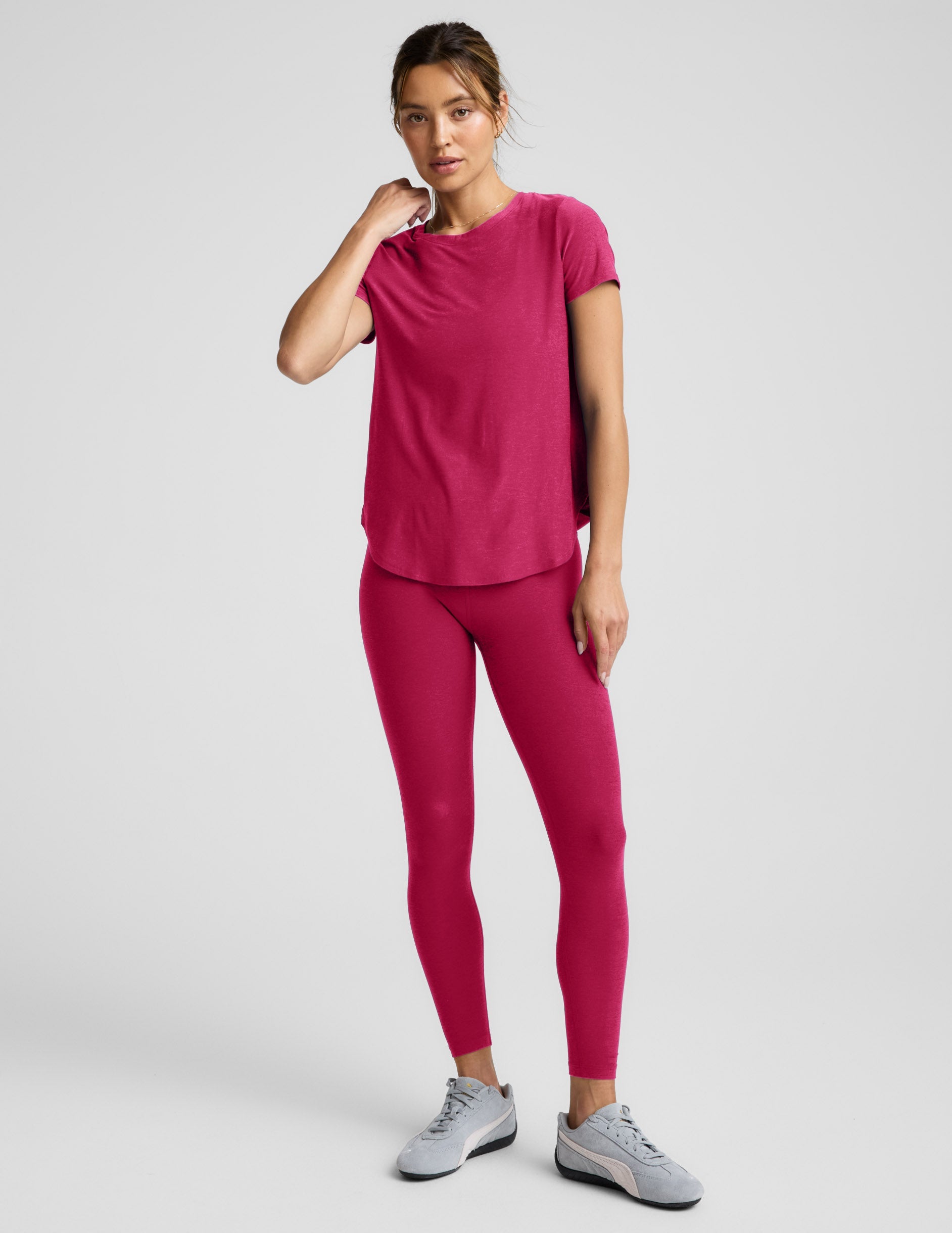 Woman wearing a red t-shirt and red leggings against a plain background.
