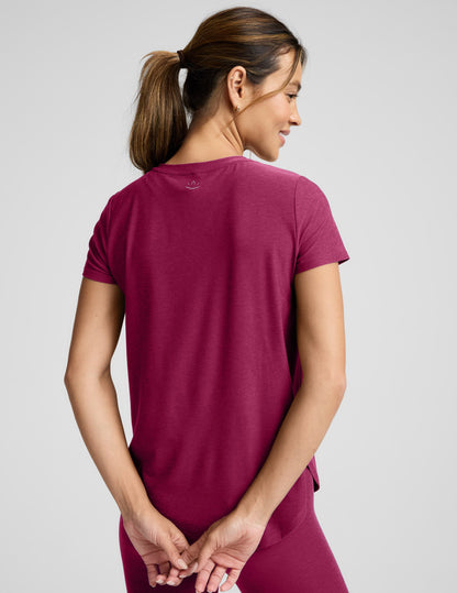 Woman in a magenta t-shirt and leggings outfit against a plain background.