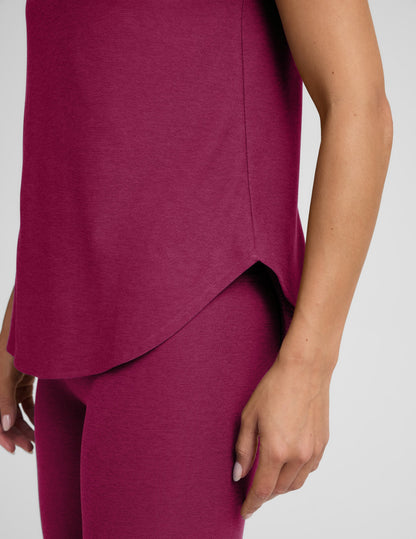 Woman in a magenta t-shirt and leggings outfit against a plain background.