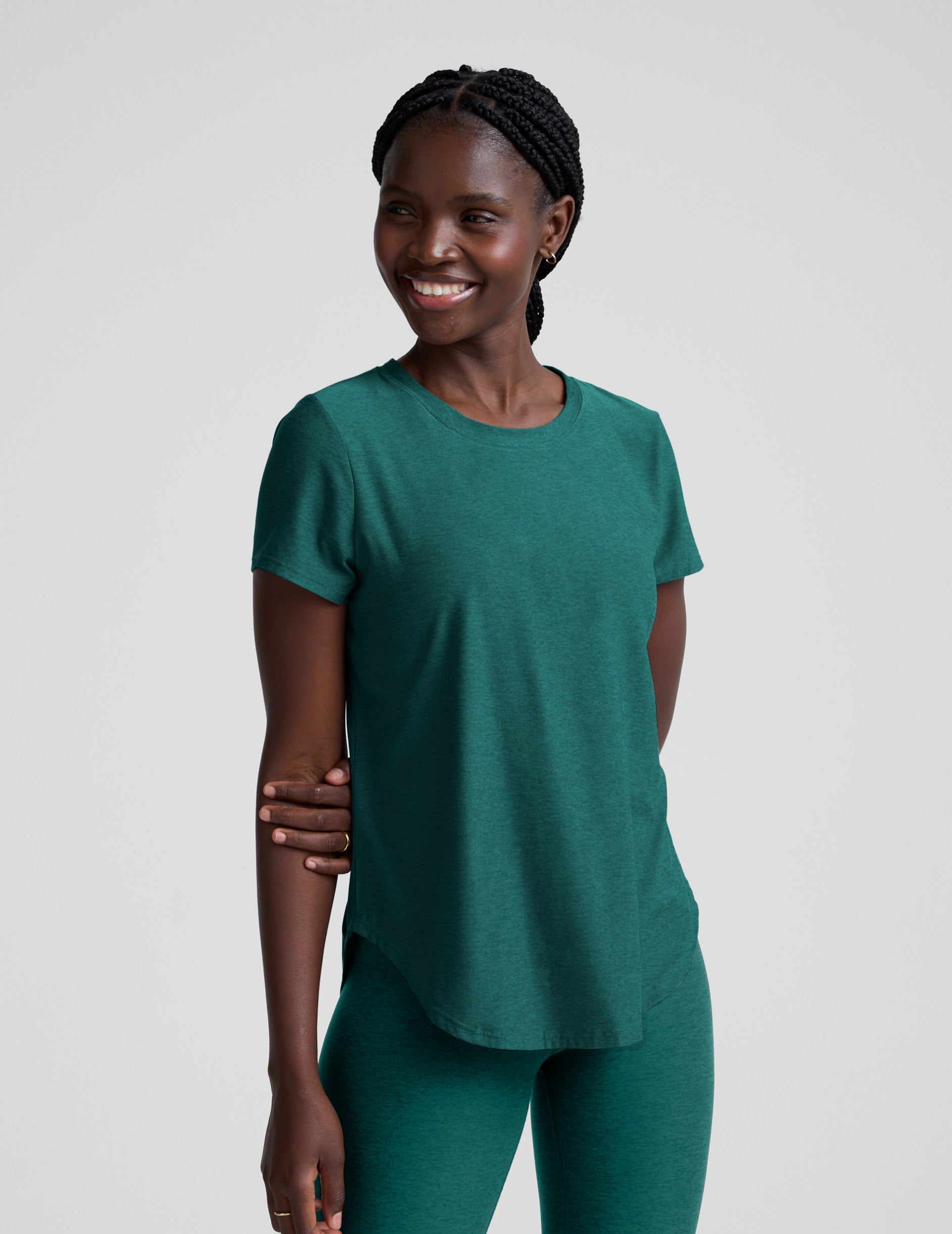 Woman wearing a green t-shirt and leggings against a plain background.