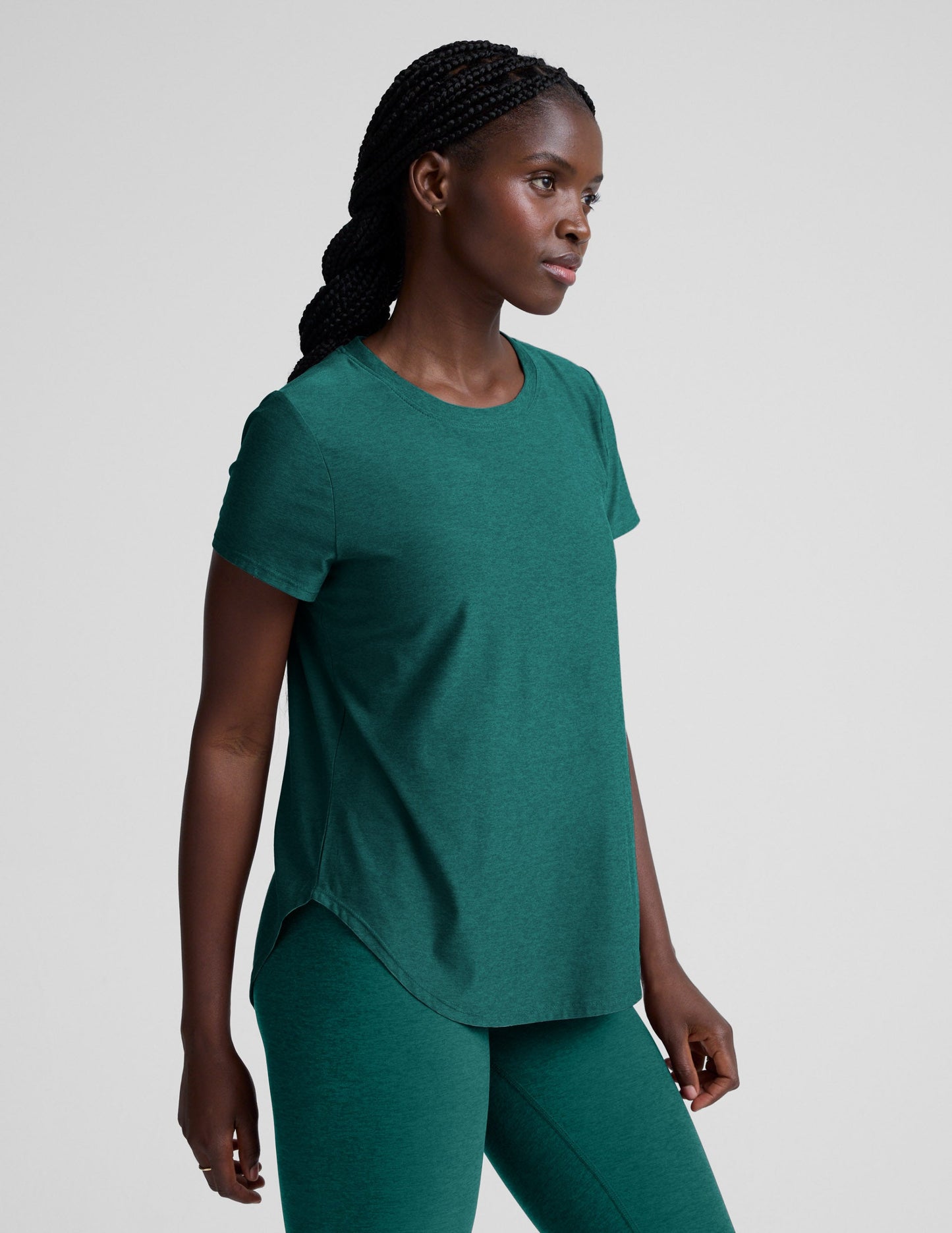 Woman wearing a green t-shirt and leggings against a plain background.