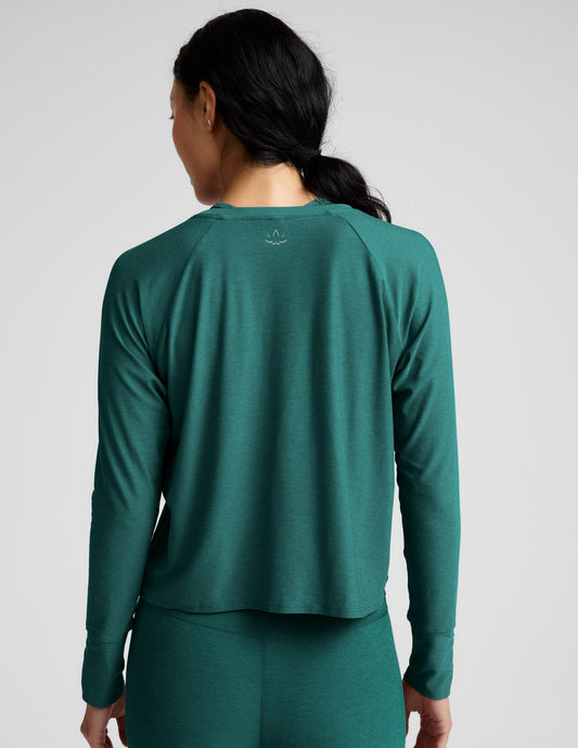 Woman wearing a teal long-sleeve top and leggings on a light gray background.