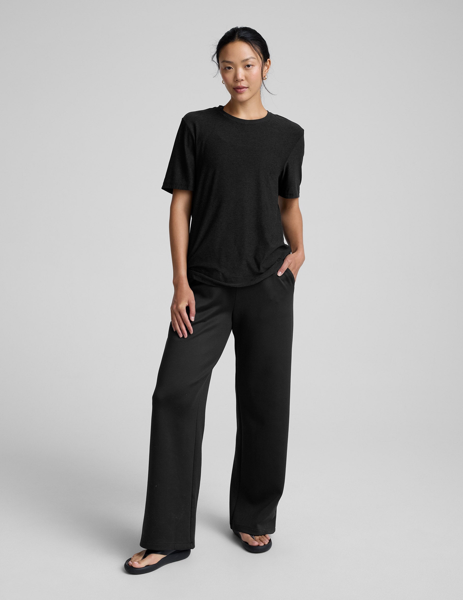 Person wearing a black t-shirt and black pants on a gray background.