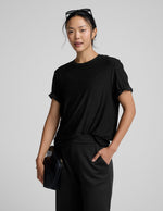 Person wearing a black t-shirt and black pants on a gray background.