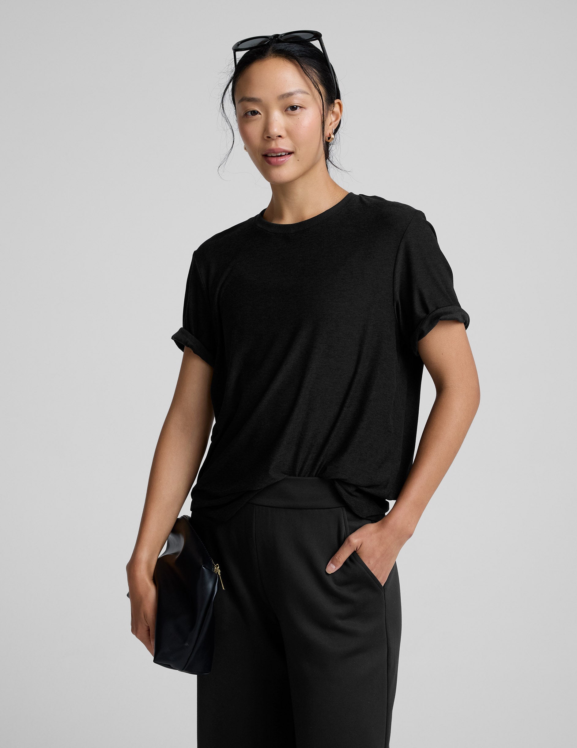 Person wearing a black t-shirt and black pants on a gray background.