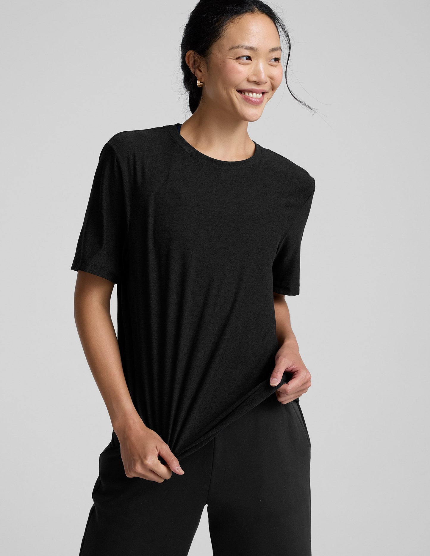 Person wearing a black t-shirt and black pants on a gray background.