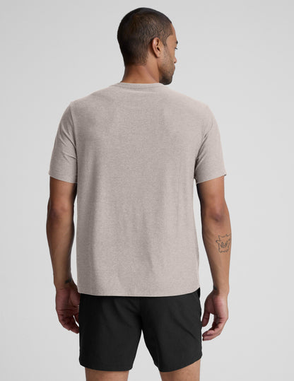 Man wearing a beige t-shirt and black shorts against a plain background.