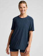model wearing a blue oversized men's t-shirt and biker shorts against a plain background.