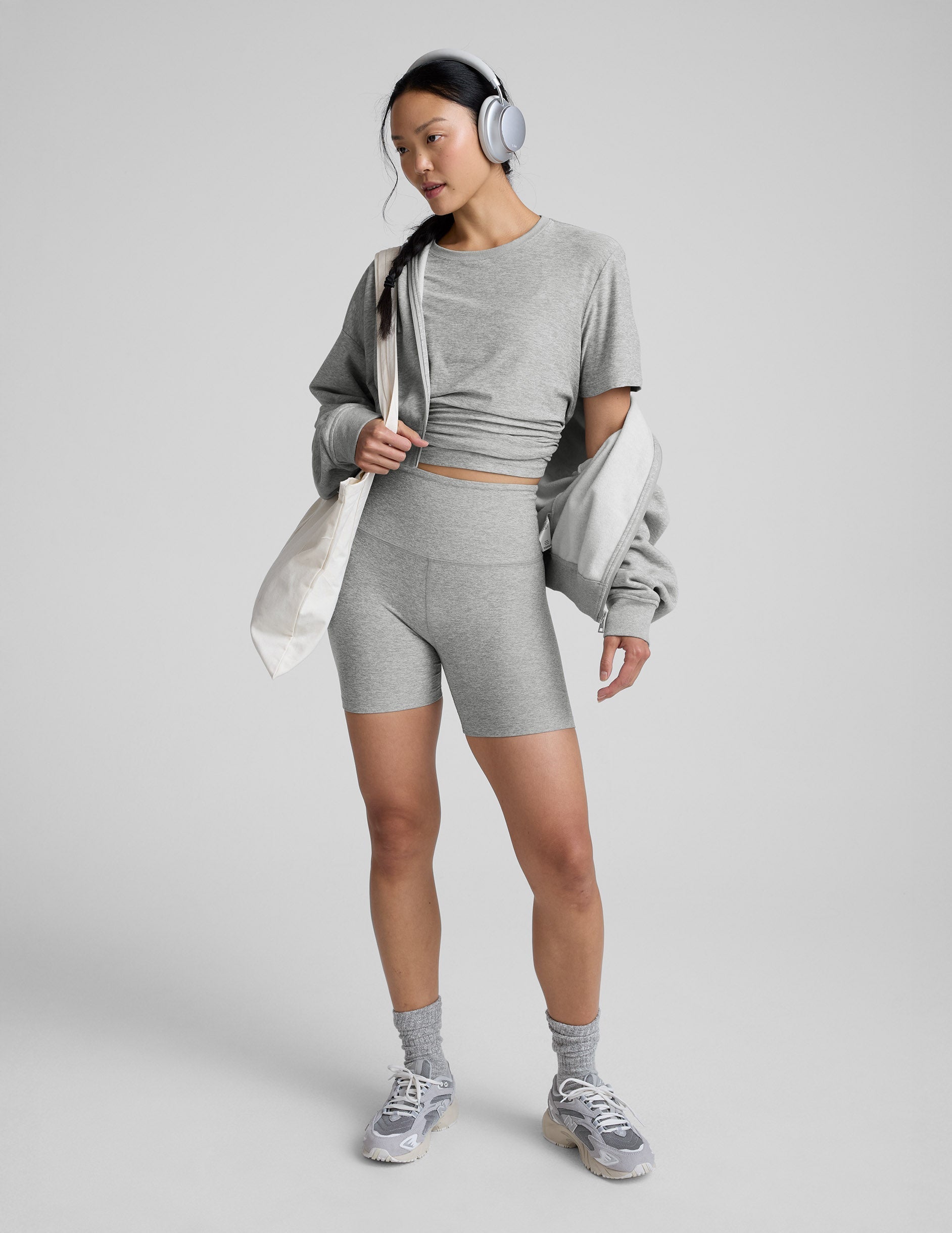 Woman wearing a gray athletic outfit on a plain background.