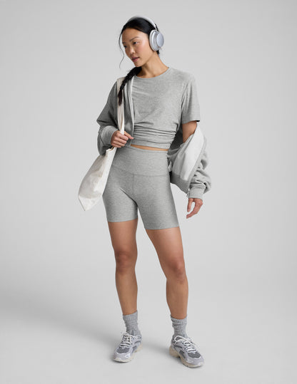 Woman wearing a gray athletic outfit on a plain background.
