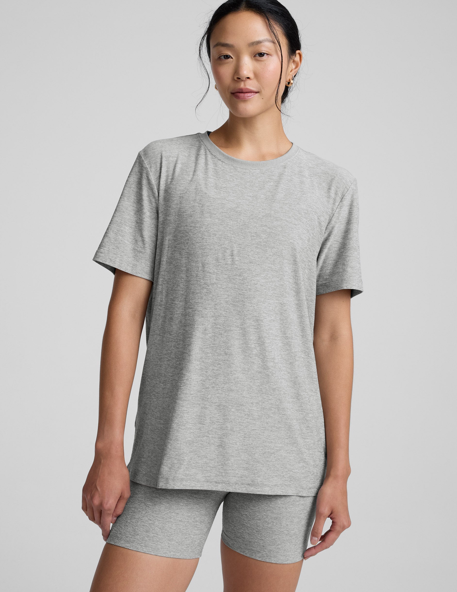 Woman wearing a gray athletic outfit on a plain background.