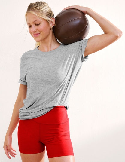 Woman wearing a gray t-shirt and red shorts against a plain background.