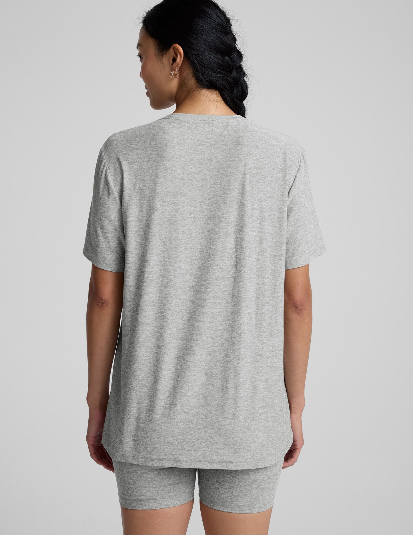 Woman wearing a gray athletic outfit on a plain background.