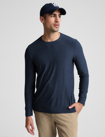 Man wearing a navy long sleeve shirt and khaki pants against a plain background.