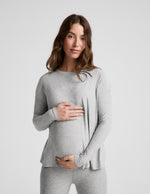 Pregnant woman wearing a gray long-sleeve top and leggings on a white background.